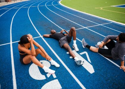 Athletes resting on a blue running track.